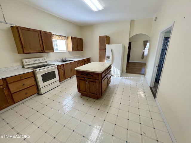 kitchen featuring white appliances, a kitchen island, a wealth of natural light, and sink