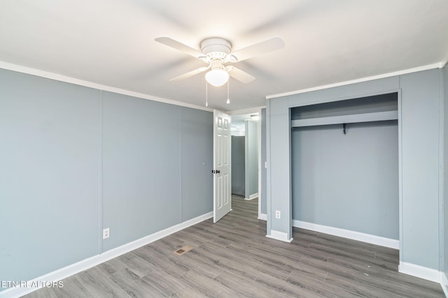 unfurnished bedroom featuring crown molding, ceiling fan, a closet, and hardwood / wood-style floors