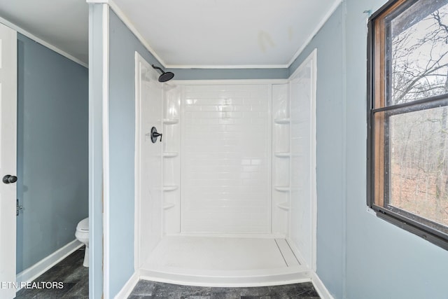 bathroom with a shower, toilet, and crown molding