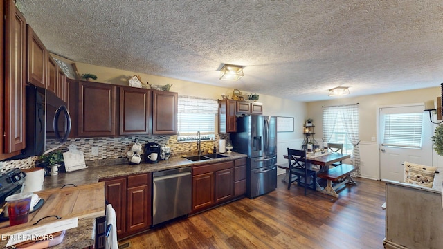 kitchen with dark wood-type flooring, sink, a textured ceiling, stainless steel appliances, and backsplash