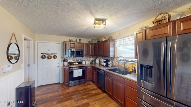 kitchen with sink, stainless steel appliances, a textured ceiling, dark hardwood / wood-style flooring, and decorative backsplash