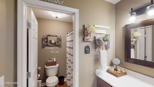 bathroom with vanity, curtained shower, toilet, and a textured ceiling