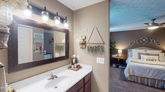 bathroom with ceiling fan, vanity, and a textured ceiling