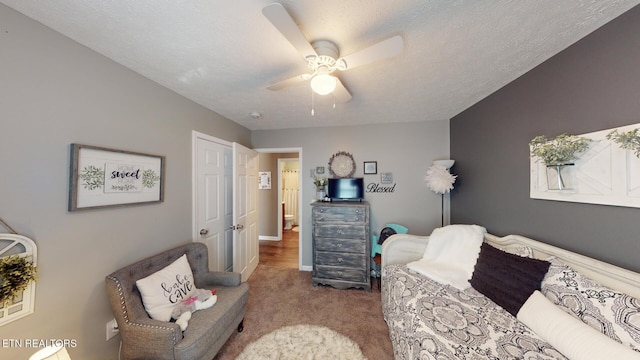 carpeted living room featuring ceiling fan and a textured ceiling