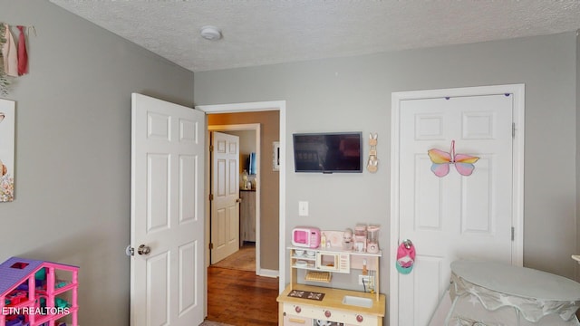 game room with dark hardwood / wood-style flooring and a textured ceiling