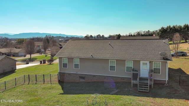 back of property with a mountain view and a lawn