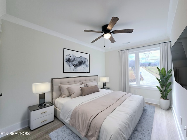 bedroom with crown molding, ceiling fan, and light hardwood / wood-style flooring