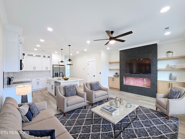 living room with sink, hardwood / wood-style flooring, ornamental molding, and ceiling fan