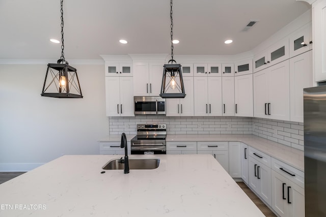 kitchen with white cabinetry, appliances with stainless steel finishes, sink, and pendant lighting