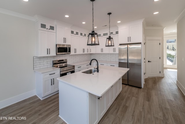 kitchen featuring sink, appliances with stainless steel finishes, an island with sink, pendant lighting, and white cabinets