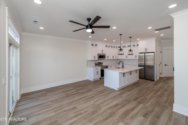 kitchen with pendant lighting, sink, a kitchen island with sink, stainless steel appliances, and white cabinets