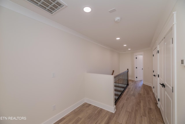 hallway with crown molding and light hardwood / wood-style floors