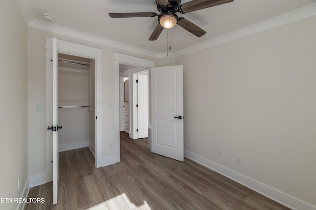 unfurnished bedroom featuring wood-type flooring, ceiling fan, crown molding, and a closet