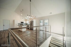 kitchen with pendant lighting, french doors, white cabinets, vaulted ceiling, and stainless steel refrigerator