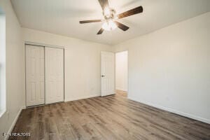 unfurnished bedroom featuring ceiling fan, a closet, and wood-type flooring