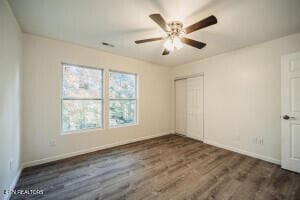 unfurnished bedroom featuring a closet, ceiling fan, and dark hardwood / wood-style flooring