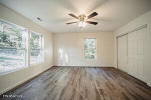 unfurnished bedroom featuring dark hardwood / wood-style floors, ceiling fan, and multiple windows