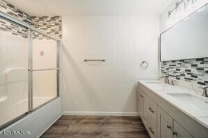 bathroom with combined bath / shower with glass door, decorative backsplash, vanity, and wood-type flooring