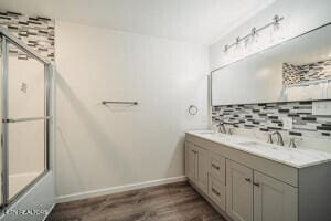 bathroom featuring tasteful backsplash, vanity, bath / shower combo with glass door, and hardwood / wood-style flooring