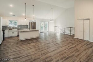 kitchen with pendant lighting, a center island, white cabinets, decorative backsplash, and stainless steel fridge