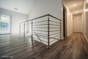 hallway with dark hardwood / wood-style floors and vaulted ceiling