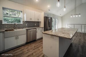 kitchen with white cabinetry, stainless steel appliances, pendant lighting, vaulted ceiling, and a kitchen island