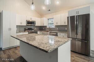 kitchen featuring appliances with stainless steel finishes, decorative light fixtures, a kitchen island, and white cabinetry