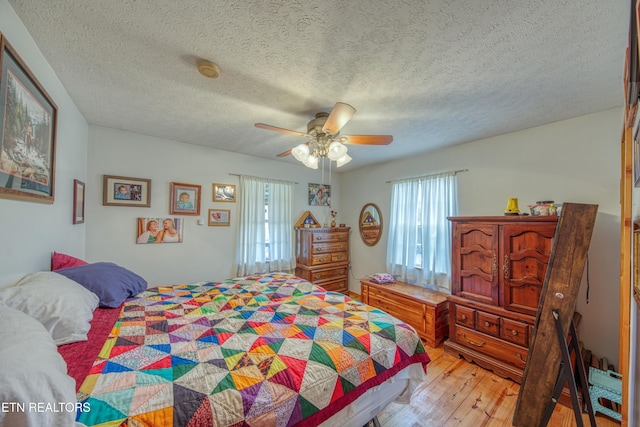 bedroom with ceiling fan, wood-type flooring, and a textured ceiling