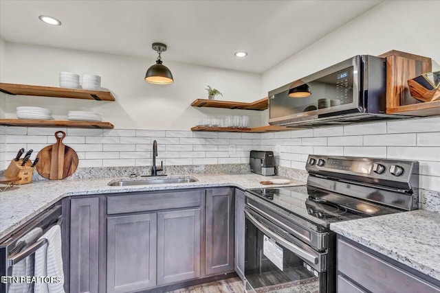 kitchen with light stone countertops, sink, hanging light fixtures, black / electric stove, and decorative backsplash