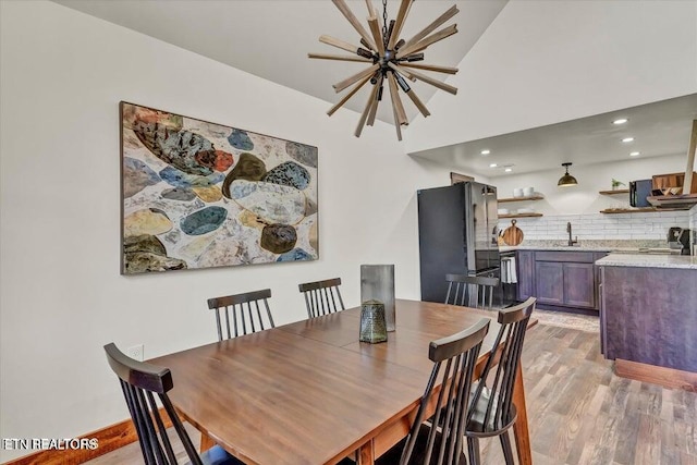 dining area with light hardwood / wood-style floors and an inviting chandelier