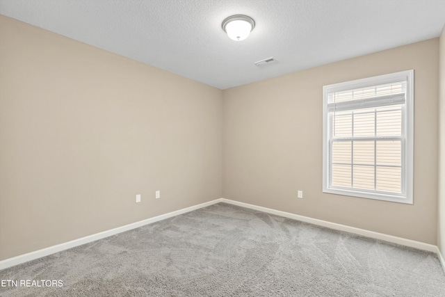 carpeted empty room featuring a textured ceiling