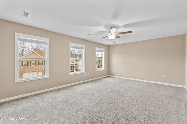 empty room featuring ceiling fan, carpet floors, and a wealth of natural light