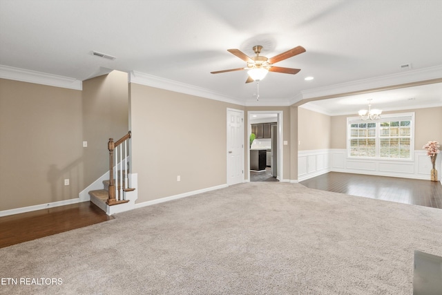 unfurnished living room with crown molding, ceiling fan with notable chandelier, and dark colored carpet