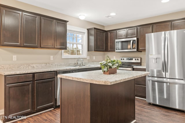 kitchen with sink, dark wood-type flooring, stainless steel appliances, dark brown cabinetry, and a kitchen island