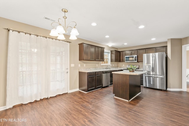 kitchen with stainless steel appliances, hanging light fixtures, dark brown cabinets, and dark wood-type flooring