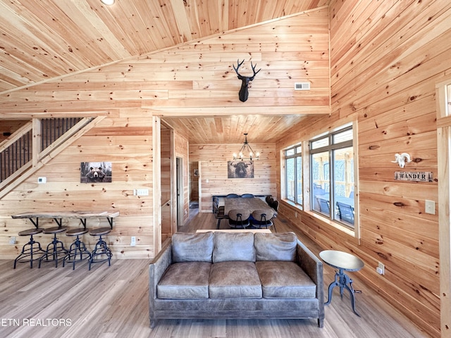 bedroom with a chandelier, wooden ceiling, wooden walls, wood finished floors, and visible vents