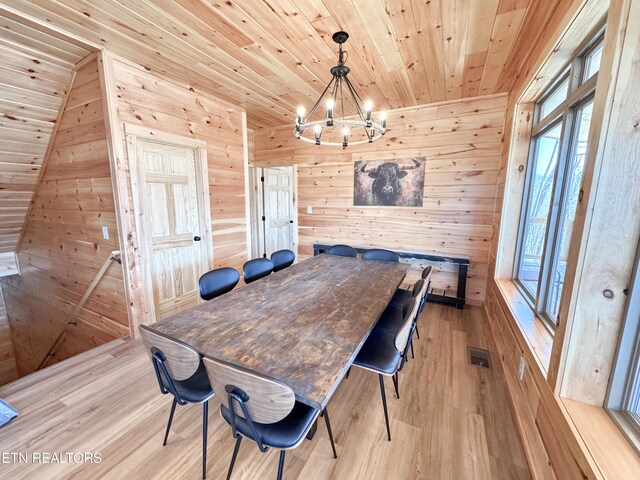 dining space with visible vents, light wood-style floors, wooden walls, a chandelier, and wooden ceiling