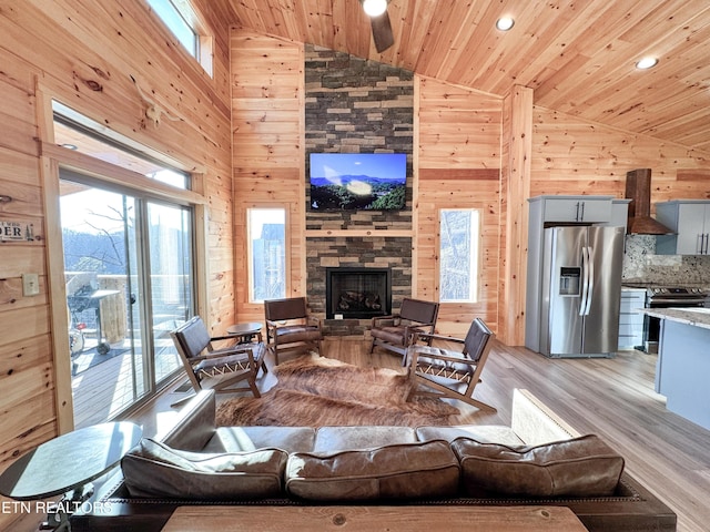 living area featuring plenty of natural light, wood walls, a fireplace, and wooden ceiling