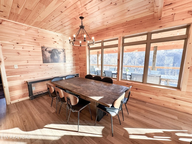 dining room with light wood-type flooring, wood walls, wood ceiling, and plenty of natural light