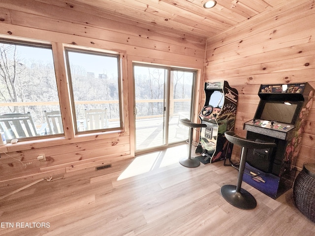 workout room featuring wood ceiling, light wood-type flooring, visible vents, and wooden walls