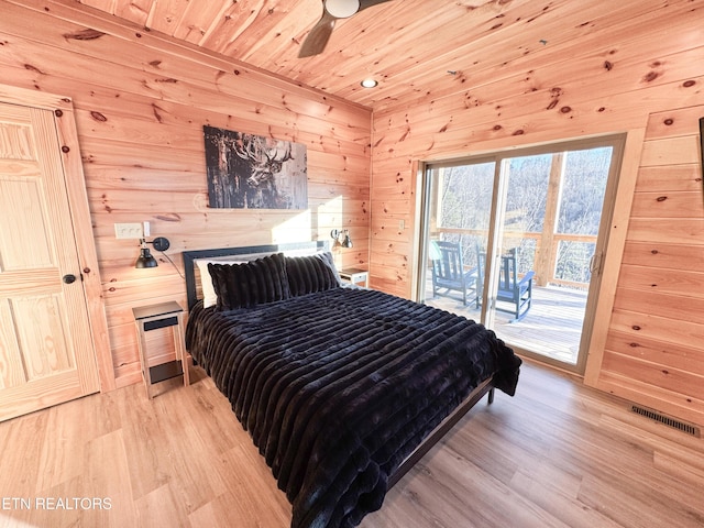 bedroom with visible vents, light wood-style floors, wood ceiling, wooden walls, and access to outside