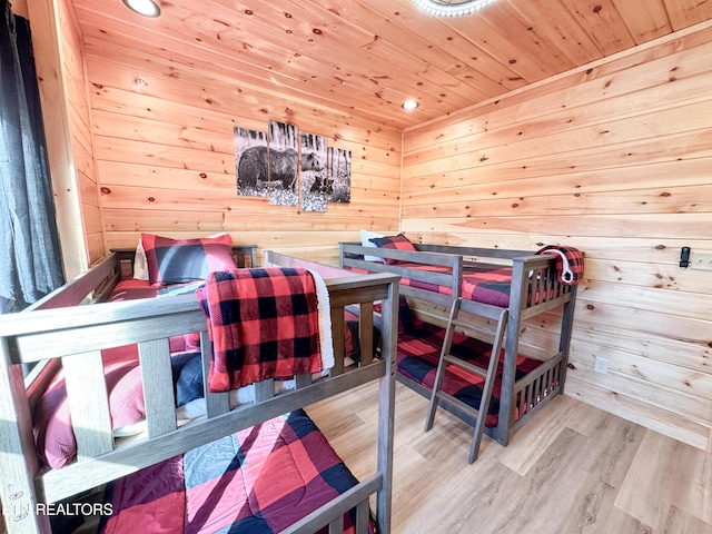 bedroom with light wood-style flooring, wood ceiling, wooden walls, and a sauna