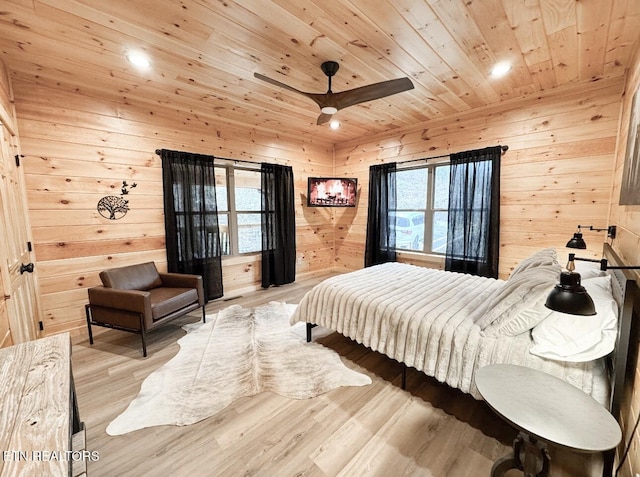 bedroom featuring wood walls, wood ceiling, light wood-style flooring, and a ceiling fan