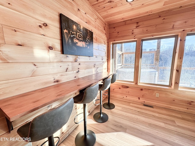 dining room with a wealth of natural light, visible vents, and wooden walls