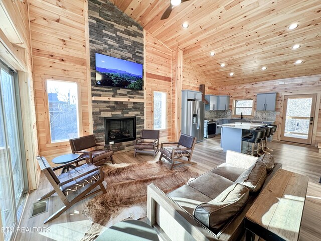 living room with wooden ceiling, wooden walls, visible vents, and a fireplace