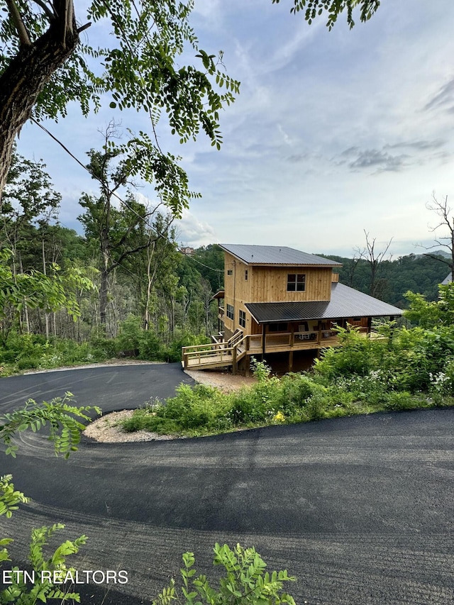 view of front of property with driveway, a deck, and metal roof