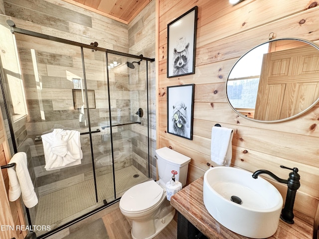 full bathroom with a stall shower, a sink, toilet, and wooden walls