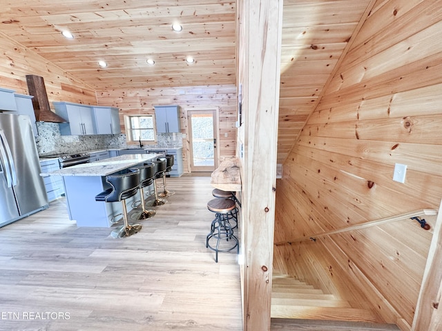 kitchen featuring lofted ceiling, stainless steel appliances, a kitchen island, and a breakfast bar