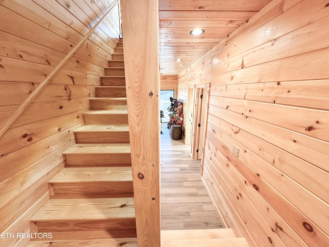 stairs with wooden ceiling, wood walls, and wood finished floors