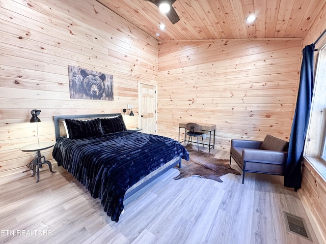 bedroom featuring wooden walls, wood finished floors, wood ceiling, visible vents, and vaulted ceiling